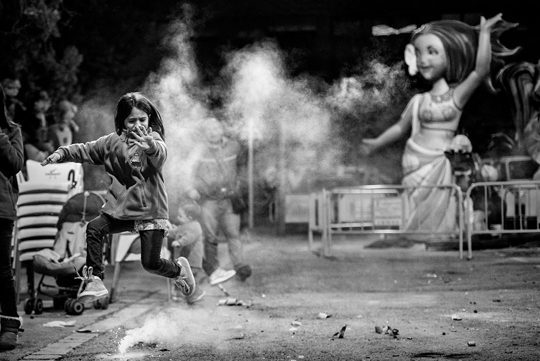 People running through smoke beside a large festival figure.